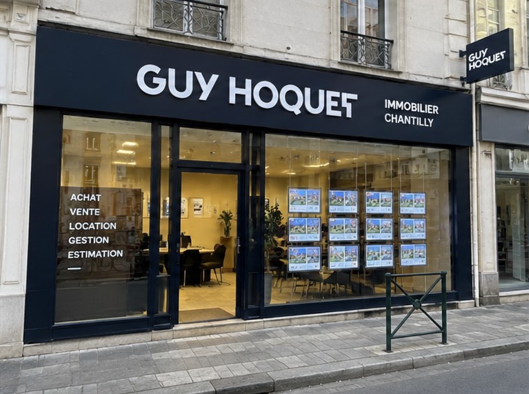 Vitrine d’une agence immobilière Guy Hoquet à Chantilly, annonces affichées en vitrine